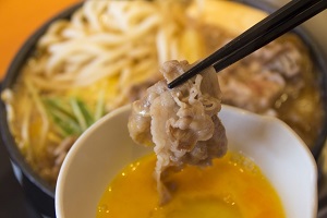 Dipping sukiyaki into raw egg